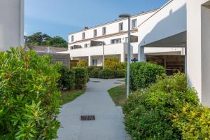 a walkway in front of a building at Résidence Prestige Odalys Le Domaine des Pins in Noirmoutier-en-l'lle