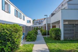 a walkway between two apartment buildings at Résidence Prestige Odalys Le Domaine des Pins in Noirmoutier-en-l'lle