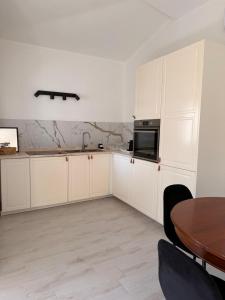 a kitchen with white cabinets and a wooden table at CasaNica - Elegant independent apartment in Torpè