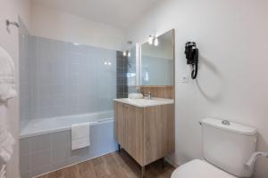 a bathroom with a toilet and a sink and a tub at Résidence Prestige Odalys Le Domaine des Pins in Noirmoutier-en-l'lle