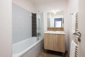 a bathroom with a tub and a sink and a shower at Résidence Prestige Odalys Le Domaine des Pins in Noirmoutier-en-l'lle