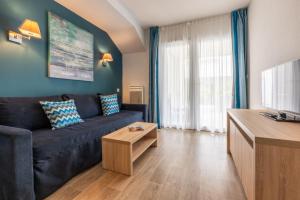a living room with a black couch and a tv at Résidence Prestige Odalys Le Domaine des Pins in Noirmoutier-en-l'lle