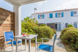 a table and chairs on the patio of a house at Résidence Prestige Odalys Le Domaine des Pins in Noirmoutier-en-l'lle
