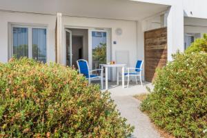 a patio with blue chairs and a table at Résidence Prestige Odalys Le Domaine des Pins in Noirmoutier-en-l'lle