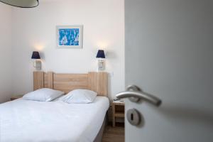 a bedroom with a white bed and a sink at Résidence Prestige Odalys Le Domaine des Pins in Noirmoutier-en-l'lle