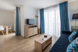a living room with a blue couch and a tv at Résidence Prestige Odalys Le Domaine des Pins in Noirmoutier-en-l'lle