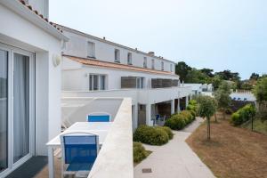 a white building with blue chairs on a balcony at Résidence Prestige Odalys Le Domaine des Pins in Noirmoutier-en-l'lle