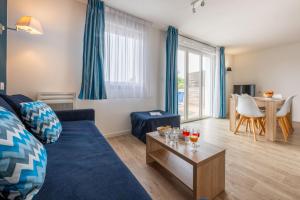 a living room with a blue couch and a table at Résidence Prestige Odalys Le Domaine des Pins in Noirmoutier-en-l'lle