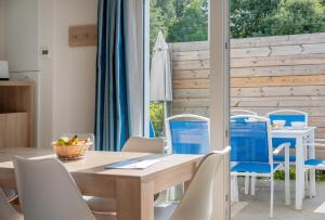 a dining room with a wooden table and chairs at Résidence Prestige Odalys Le Domaine des Pins in Noirmoutier-en-l'lle