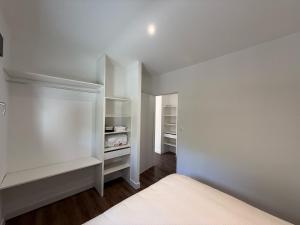 a bedroom with white walls and a white bed at Montelimar Location in Montélimar