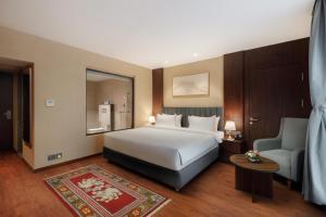 カトマンズにあるRoyal Tulip Kathmanduのベッドとソファと椅子のある寝室