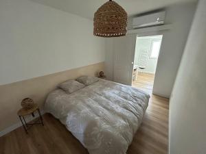 a bedroom with a white bed and a chandelier at Au Soleil Couchant in Wimille