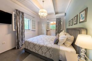 een slaapkamer met een bed en een kroonluchter bij Arilia Country Cottage in Danilia