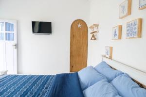 a bedroom with a bed with blue sheets and a tv at WabiSabi House in Gandok