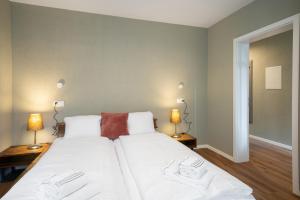 a bedroom with a large white bed with two lamps at BetweenLakes Apartment 1st floor in Interlaken