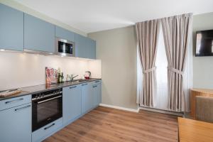 a kitchen with blue cabinets and a window at BetweenLakes Apartment 1st floor in Interlaken