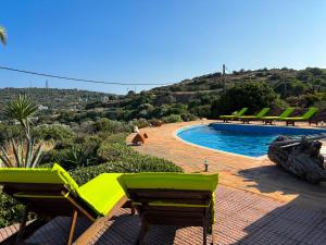 a pool with two green chairs and a swimming pool at Tethys Apartments Karfas in Chios