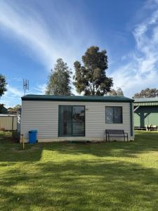 a small white house with a bench in a yard at Kyalite Caravan Park in Kyalite +7 photos