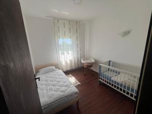 a small bedroom with a crib and a window at Apartman FM in Arandjelovac