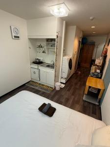 a bedroom with a white bed and a kitchen at 華宝民泊1 in Osaka