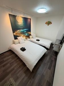 two beds in a room with a painting on the wall at 華宝民泊1 in Osaka