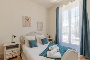 a bedroom with a bed with blue curtains and a window at Le Monnaie - Appartement lumineux face au Château de Pau in Pau