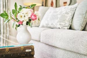 a white vase with flowers on a table next to a couch at La Ferme D'Augustin in Saint-Tropez