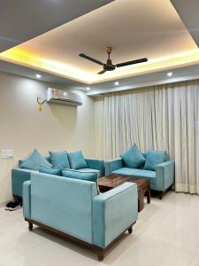 un soggiorno con divani blu e soffitto di Skylar Home a Zirakpur