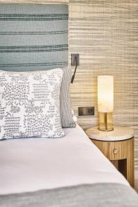 a bed with a pillow and a lamp on a night stand at La Ferme D'Augustin in Saint-Tropez