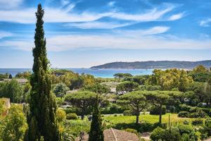 a view of a park with trees and the ocean at La Ferme D'Augustin in Saint-Tropez