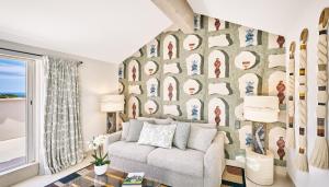 a living room with a couch and a wall of pictures at La Ferme D'Augustin in Saint-Tropez