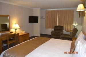 ein Hotelzimmer mit einem Bett, einem Schreibtisch und einem Stuhl in der Unterkunft Western Inn in Tremonton
