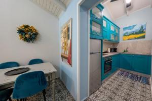 een keuken met blauwe kasten en een tafel en stoelen bij Arilia Country Cottage in Danilia
