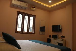 a bedroom with a bed and a window and a television at GD Palace in Jātni