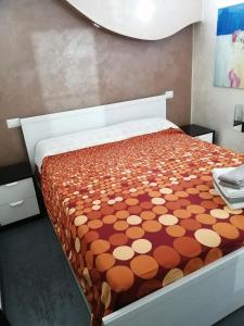 a bedroom with a bed with an orange and white comforter at Monica & Rocco's House in Venaria Reale