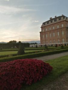 a large building with a bunch of red flowers in front at Monica & Rocco's House in Venaria Reale