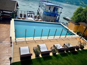 a swimming pool with chairs and a boat in the water at Mustaciosul Dunarii in Eşelniţa