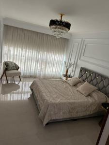 a bedroom with a large bed and a chandelier at ORAN MOBILART 4 PIECES MODERN apartement in Oran