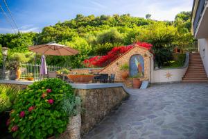 a patio with a table and an umbrella and flowers at Villa Mafalda in Pietra Ligure