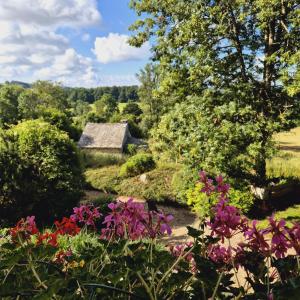 a garden with flowers and an old stone cottage at Le Mas de Rigoulac SPA sur réservation et table d'hôtes tout les jours sauf les jeudis et les dimanches in Bouyssounouse +38 photos