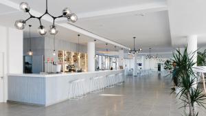 Un vestíbulo con un bar con taburetes blancos. en AluaSoul Ibiza - Adults only, en Es Canar