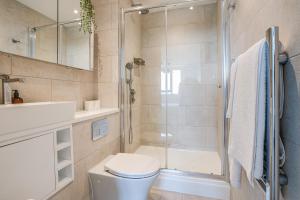 a bathroom with a shower and a toilet and a sink at Athera - Walthamstow Central Sub-Penthouse 2 bedroom, 2 bathroom Incredible views! in London +33 photos