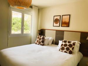 a bedroom with a white bed with pillows and a window at Hôtel Golf Fontcaude in Montpellier
