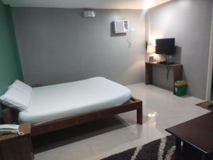 a small bedroom with a bed and a television at Hope Pension House - Danao in Danao City