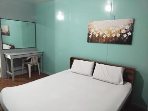 a bedroom with a white bed and a desk at Hope Pension House - Danao in Danao City