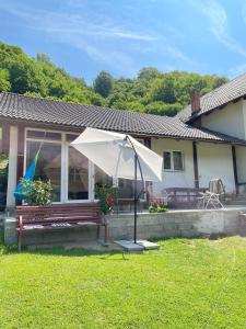 a house with a bench and an umbrella in the yard at Casa Din Lunca in Poiana Mărului
