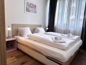 une chambre avec un lit avec des draps blancs et une fenêtre dans l'établissement Apartment Nera - Zell am See, à Zell am See