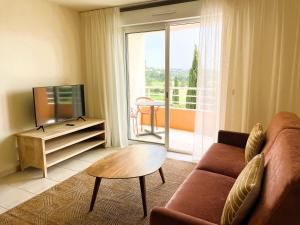 a living room with a couch and a tv and a table at Hôtel Golf Fontcaude in Montpellier