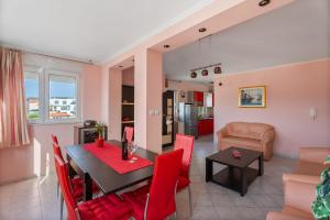 a dining room and living room with a table and red chairs at Summer Memories in Okrug Gornji +17 photos