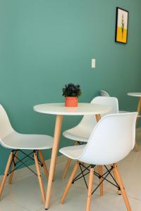 富国Ju-Jo Homestay的一张桌子,上面有白色的椅子和盆栽植物